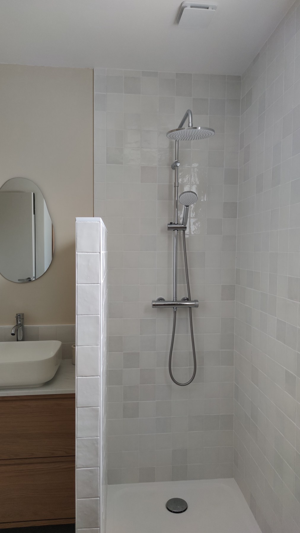 Salle d’eau réalisée avec douche, cloison carrelée et meuble vasque en bois